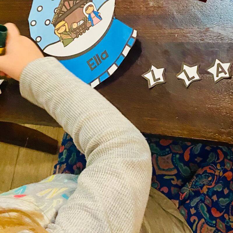 child putting together snow globe name craft