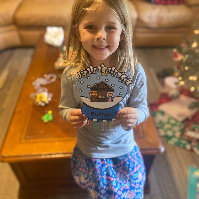 child holding finished snow globe name craft